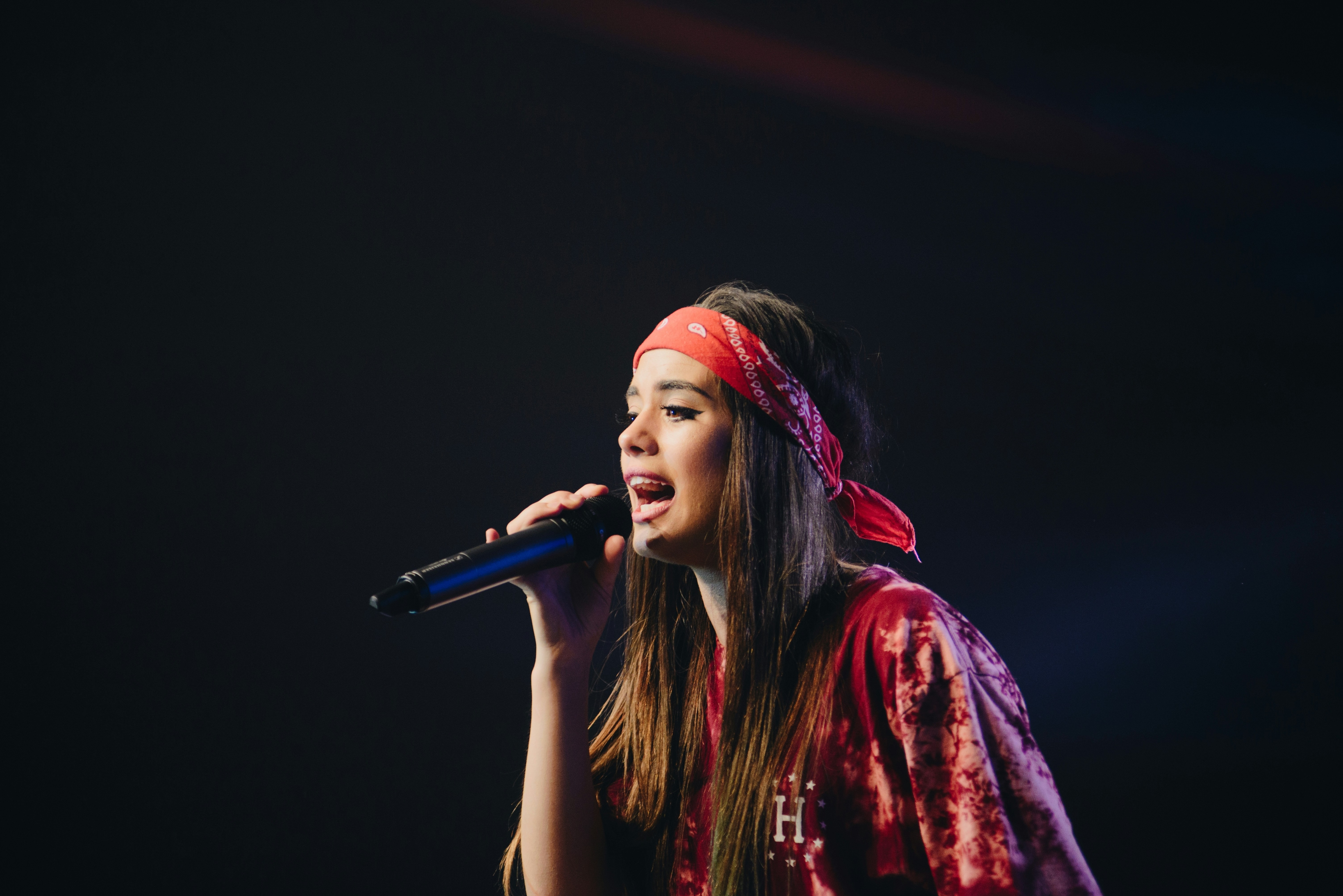 Uma cantora no palco com um fundo preto.